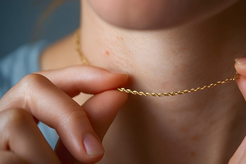 A woman admiring a gold rope chain necklace around her neck, close-up view.